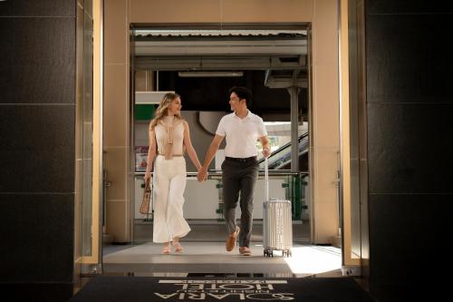a man and a woman walking through a doorway with their luggage at Solaria Nishitetsu Hotel Bangkok in Bangkok