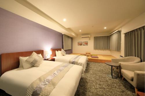 a hotel room with two beds and a chair at Hotel Tokyo Trip Ueno Nishi Nippori in Tokyo