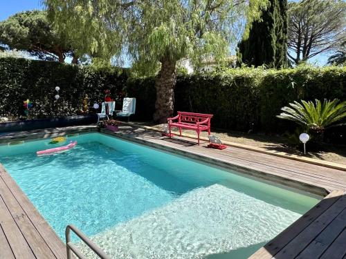 une piscine avec un banc rouge dans une cour dans l'établissement Bas de villa avec piscine privée, grande terrasse, proche village et plage, BBQ, terrain de pétanque - FR-1-726-52, à La Croix-Valmer