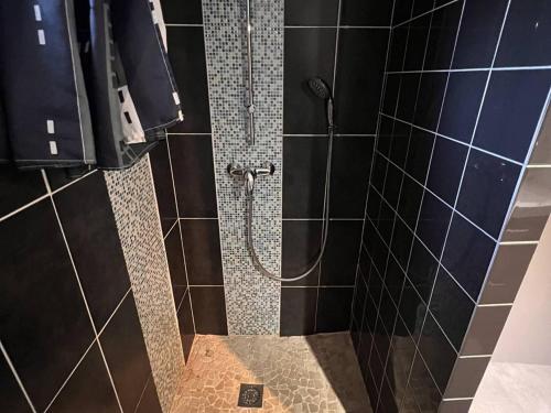 La salle de bains est pourvue d'une douche avec du carrelage noir. dans l'établissement Bas de villa avec piscine privée, grande terrasse, proche village et plage, BBQ, terrain de pétanque - FR-1-726-52, à La Croix-Valmer