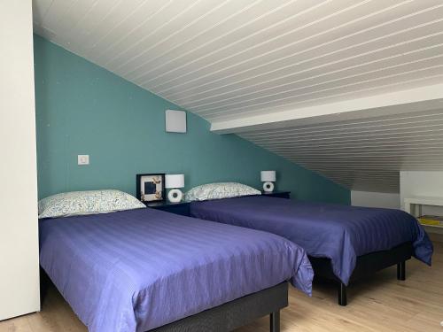 deux lits dans une chambre aux murs bleus dans l'établissement Maisonnette de Vacances à 200m de la Plage avec Terrasse à Saint-Georges-de-Didonne - FR-1-550-84, à Saint-Georges-de-Didonne