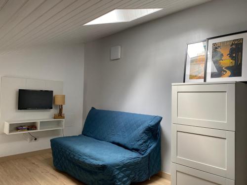 Cette chambre comprend une chaise bleue et une télévision. dans l'établissement Maisonnette de Vacances à 200m de la Plage avec Terrasse à Saint-Georges-de-Didonne - FR-1-550-84, à Saint-Georges-de-Didonne