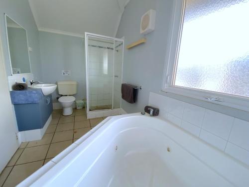 La salle de bains est pourvue d'une baignoire blanche et de toilettes. dans l'établissement Osprey Holiday Village Unit 222 1 Bedroom, à Exmouth