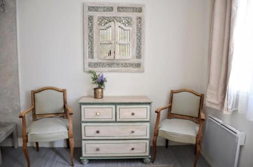 une chambre avec deux chaises, une commode et un miroir dans l'établissement Petite chambre avec 2 lits dans maison d'artiste centre ville, à Bernay