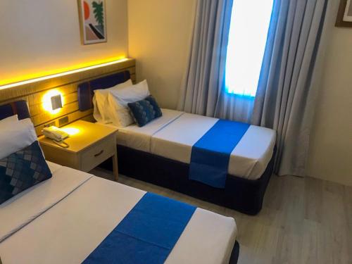 a hotel room with two beds and a window at Cebu Uncle Toms Cabin Hotel powered by Cocotel in Cebu City
