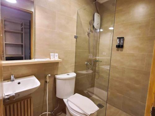 a bathroom with a shower and a toilet and a sink at Cebu Uncle Toms Cabin Hotel powered by Cocotel in Cebu City