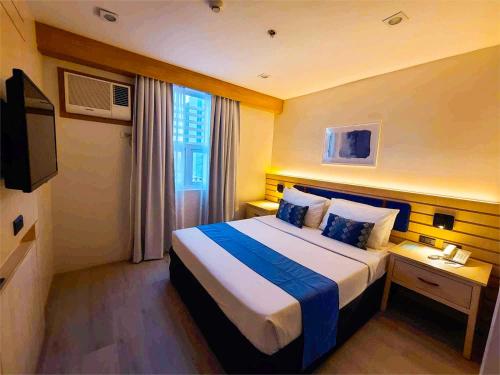 a hotel room with a bed and a television at Cebu Uncle Toms Cabin Hotel powered by Cocotel in Cebu City