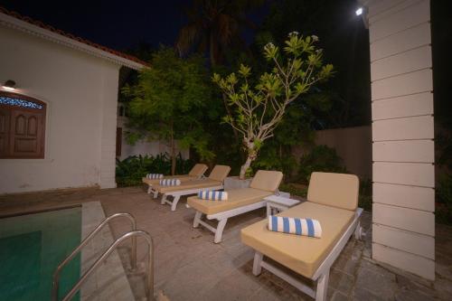 a row of lounge chairs next to a swimming pool at night at Idda Boutique Villa - Four Bedroom Luxury Villa with Private Pool Near the Beach in Ahangama