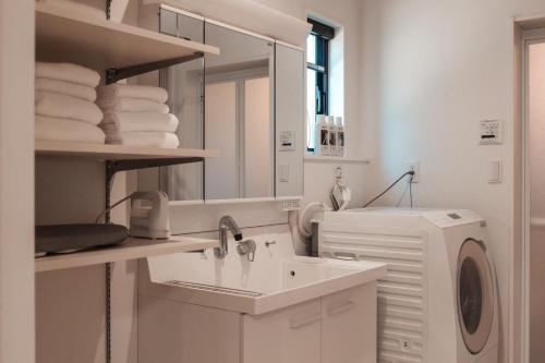a bathroom with a sink and a washing machine at Mova Villa Okino in Kikuyo