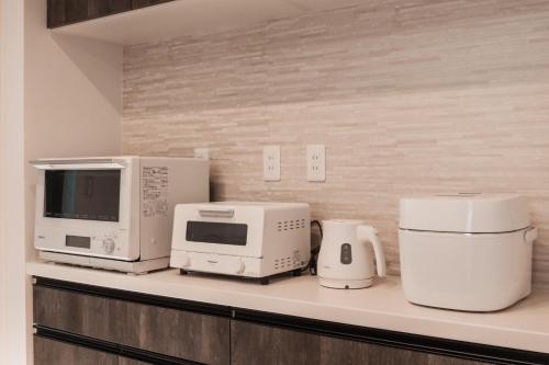 a kitchen with two microwaves and appliances on a counter at Mova Villa Okino in Kikuyo