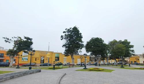 a park with benches and trees in front of a yellow building at Casona Turística Gonzales in Lima