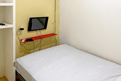 a small room with a bed and a tv on a wall at Backpacker Homestay Jatisampurna Redpartner in Bekasi