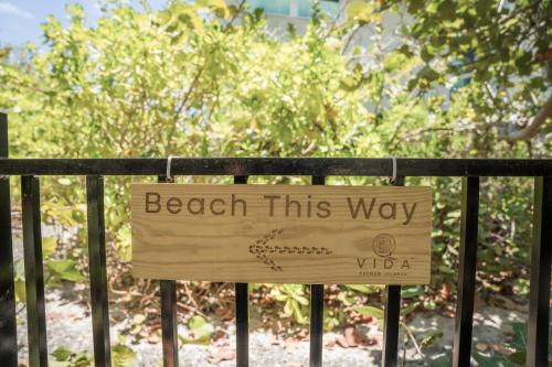 a sign that reads beach this way on a fence at VIDA Cayman Luxury Boutique Eco Hotel in West Bay