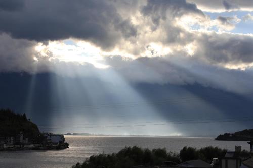 a cloudy sky with rays of light on the water at Dali Fish Inn Sea View Hotel in Dali