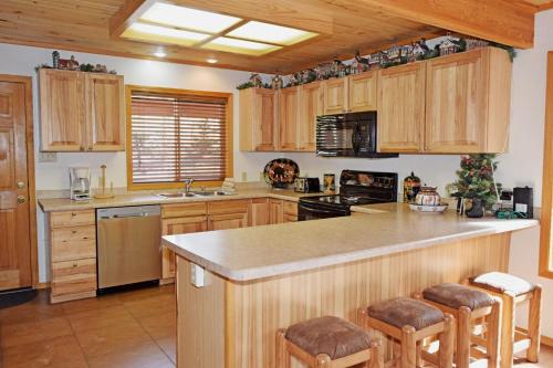 una cucina con armadi in legno e un'isola con sgabelli da bar di Deer Mountain Lodge - Hot Tub - WiFi - Washer - Dryer - Fireplace a Red River