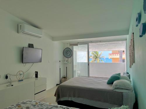 a bedroom with a bed and a tv and a window at Marina del Sol 402 Vista al Mar in Mazatlán