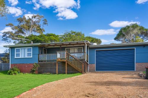 a home with a blue house with a garage at 58 Wallaga Lake Road in Bermagui