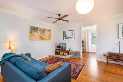 a living room with a blue couch and a ceiling fan at 58 Wallaga Lake Road in Bermagui