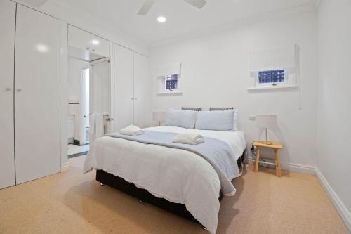 a white bedroom with a bed and a mirror at The Hideaway - Charming Cottage, Entertaining Area in Wagga Wagga