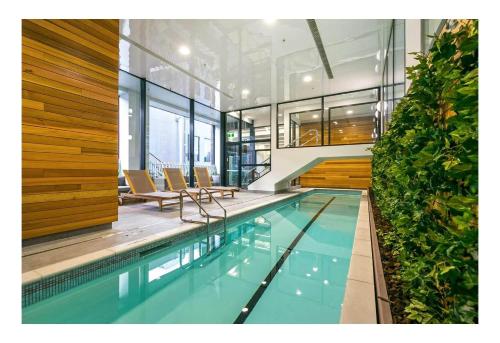 a swimming pool in a building with chairs at Spacious Skytower view and Seaview 2 BDR 2 BTH Apartment in Auckland
