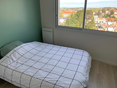 une chambre avec un lit et une grande fenêtre dans l'établissement Appartement T3 classé 3 étoiles, à Bayonne