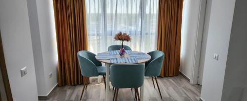 a table with chairs and a vase of flowers on it at Aphrodite Olimp - Luxury apartment with sea view & pool in Olimp