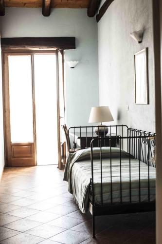 a bedroom with a bed with a lamp and a window at Azienda Agrituristica Alcastlè in Montabone