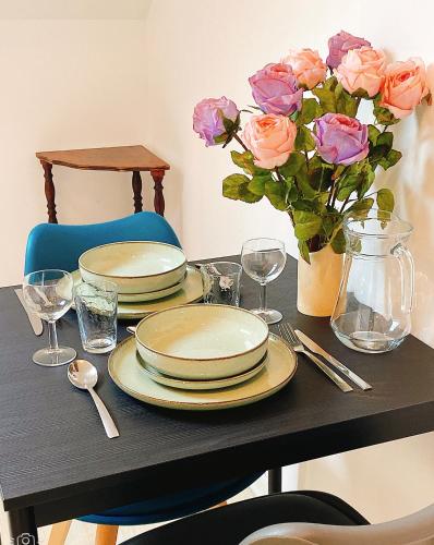 une table avec des assiettes, des fleurs et un vase de roses dans l'établissement Pacello studio, à Amboise