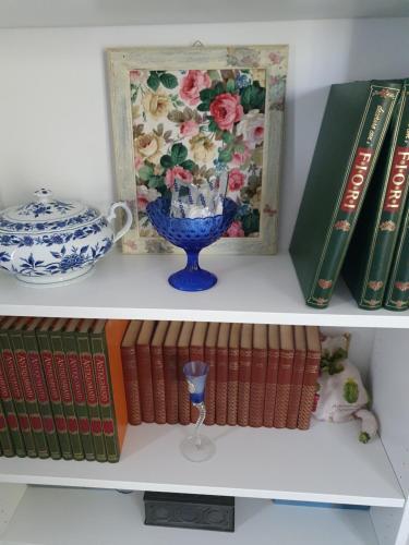 a shelf with books and a picture and a vase at la Bellavita rooms in Caltanissetta