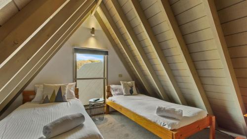 two beds in a room with a window at Aaragon in Dinner Plain
