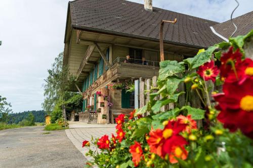 a house with red flowers in front of it at Ferienwohnung auf Bauernhof mit Hotpot und Sauna in Sumiswald