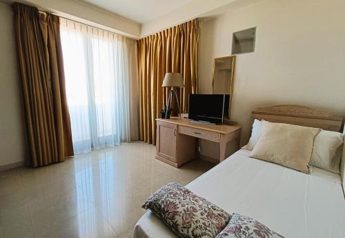 a bedroom with a bed and a desk with a television at UNICO Albatres Palace Salento by Life Resorts in San Vito dei Normanni