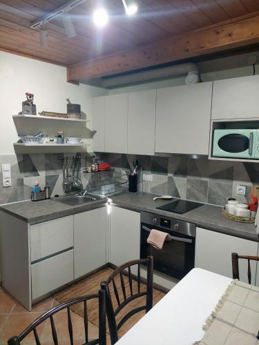 a kitchen with white cabinets and a table and chairs at The Cocoon and olives Hut in Koropi