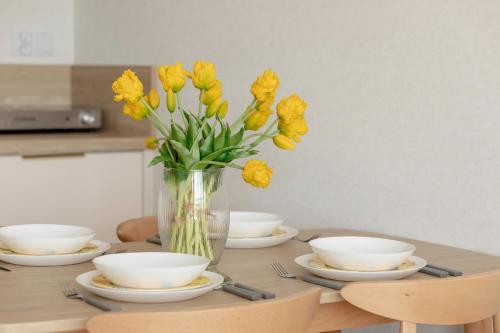 a vase of yellow flowers sitting on top of a table at Sun & Beach Apartments Bel Mare with Parking by Noclegi Renters in Międzyzdroje