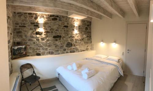 a bedroom with a white bed and a stone wall at Footpath House / Ολόκληρο σπίτι στο Μεγάλο Χωριό in Méga Khoríon