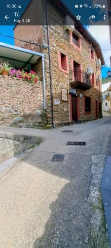 a brick building with red windows and a balcony at Casa Rural El Chorritero in Ovejuela