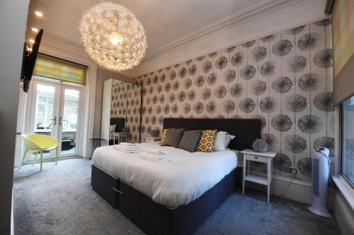 a bedroom with a large bed and a chandelier at Courtyard Mews - 2 large en suite bedrooms, Garden - Harrogate Holiday Apartments in Harrogate