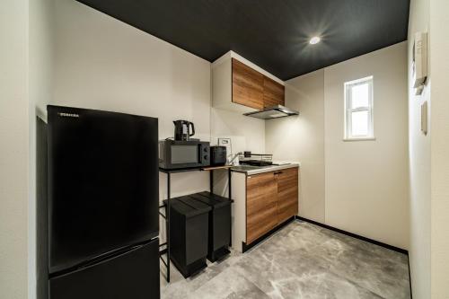 a kitchen with a black refrigerator and a microwave at 91, Honancho A, Entire house for rent, 方南町A in Tokyo
