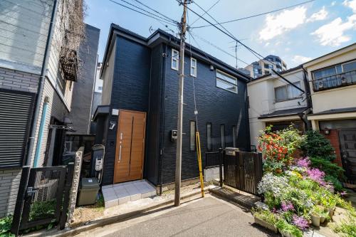 a black house with a wooden door on a street at 91, Honancho A, Entire house for rent, 方南町A in Tokyo