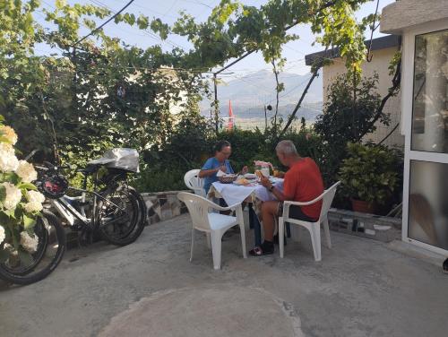 two men sitting at a table eating food at RONDO Guesthouse in Gjirokastër