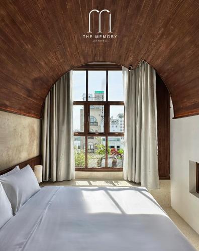 a bedroom with a bed and a large window at The Memory - Danang in Da Nang