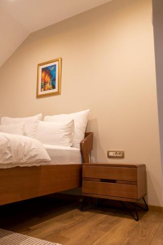 a bed with white sheets and a picture on the wall at Motel & Restoran Sunce in Busovača