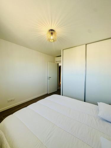 - une chambre avec un grand lit blanc et un lustre dans l'établissement Magnifique 2 pièces vue mer, à LʼÎle-Rousse