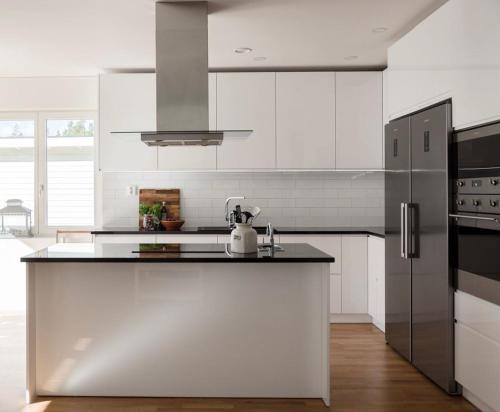 a kitchen with white cabinets and a black refrigerator at BresseInn in Enköping