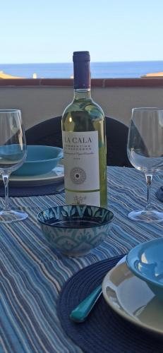 a bottle of wine sitting on a table with glasses at HAIKU HOME in Cala Gonone