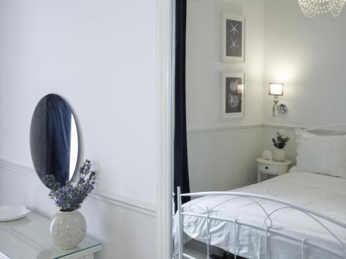 a white bedroom with a bed and a mirror at Apartments IVO in Stomorska