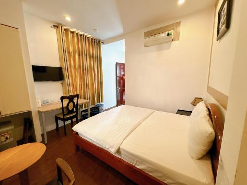 a bedroom with a bed and a table and a desk at Khách sạn Nam Môn in Can Tho