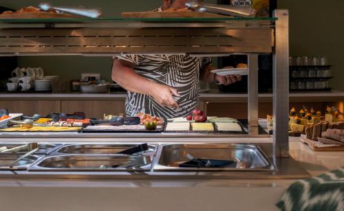a person standing in a kitchen preparing food at Hotel Santanyi Port in Cala Figuera