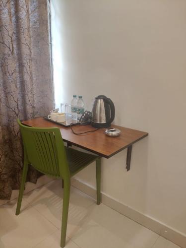 a wooden table with a tea kettle and a green chair at Treebo Park Palace in Guwahati
