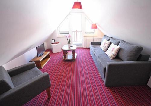 a living room with two couches and a red carpet at Gościniec Malinówka in Krzeszna